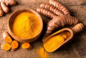 benefícios cúrcuma moída e pedaço da raiz marrom inteira